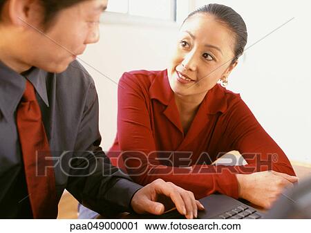 Stock Image - Man and woman sitting side by side, man's hand on keyboard. Fotosearch