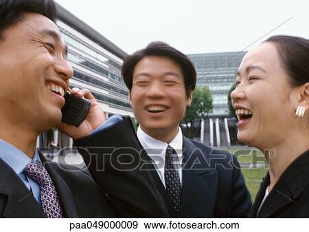 Three businesspeople laughing, one holding cell phone View Large Photo Image Stock Photo - Three businesspeople laughing, one holding cell phone. Fotosearch