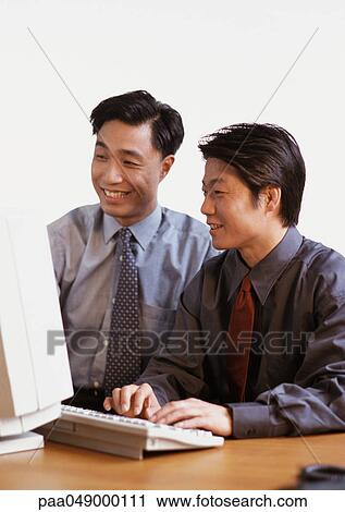 Stock Image - Two men looking at computer screen. Fotosearch