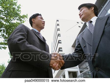 Two men shaking hands, low angle view View Large Photo Image Stock Photography - Two men shaking hands, low angle view. Fotosearch