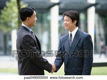 Picture - Two men shaking hands, outside. Fotosearch