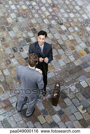 Two men standing face to face on cobblestones, elevated view View Large Photo Image Stock Photograph - Two men standing face to face on cobblestones, elevated view. Fotosearch