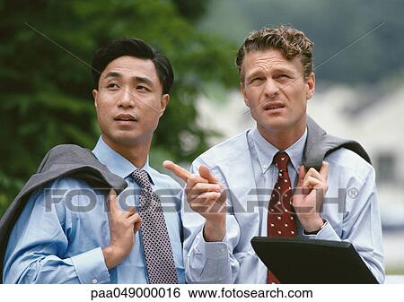 Two men standing outside, holding jacket over shoulder View Large Photo Image Stock Photograph - Two men standing outside, holding jacket over shoulder. Fotosearch