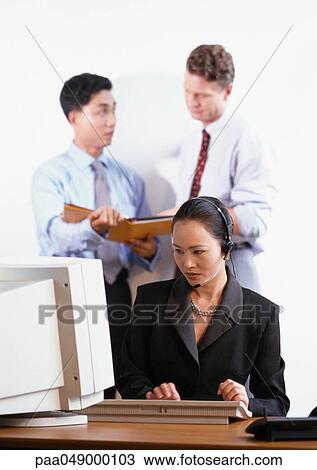 Woman looking at computer, two men in background View Large Photo Image Stock Image - Woman looking at computer, two men in background. Fotosearch