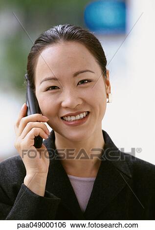 Woman using cell phone, smiling at camera, portrait View Large Photo Image Stock Photograph - Woman using cell phone, smiling at camera, portrait. Fotosearch