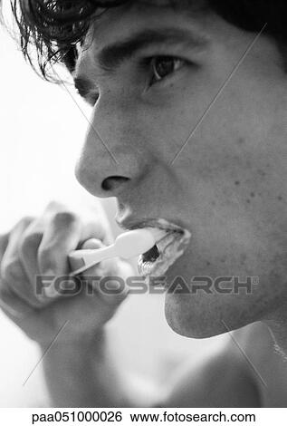 Stock Photograph - Man brushing teeth, close-up, b&w. Fotosearch