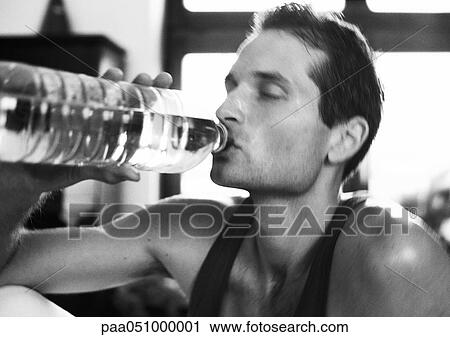 Stock Image - Man drinking from bottle, close-up, b&w. Fotosearch