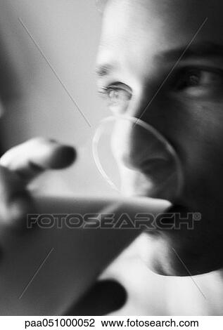 Stock Image - Man drinking from glass, close-up, blurred, b&w. Fotosearch