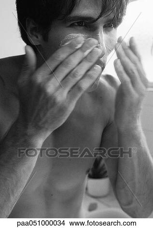 Picture - Man putting cream on face, b&w. Fotosearch