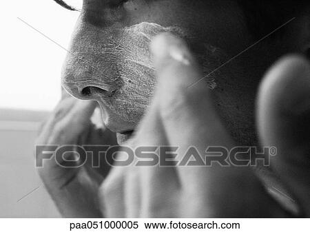 Stock Photography - Man putting cream on face, close-up, b&w. Fotosearch
