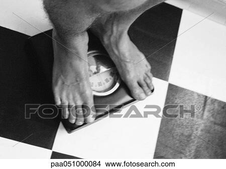 Man standing on scale, lower section, high angle view, b&w View Large Photo Image Picture - Man standing on scale, lower section, high angle view, b&w. Fotosearch