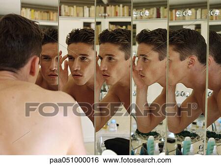 Stock Photograph - Man touching eyebrow, focus on multiple reflections in mirrors. Fotosearch