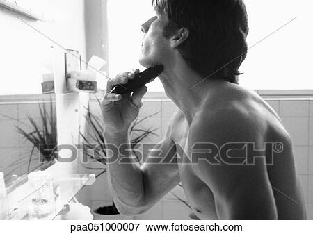 Stock Photo - Man using electric razor, side view, b&w. Fotosearch