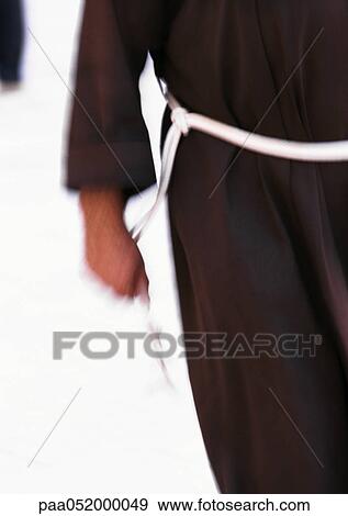 Stock Photo - Israel, Jerusalem, Franciscan monk holding belt rope, mid-section, blurred. Fotosearch