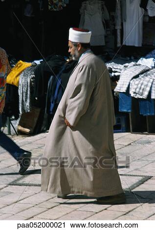 Stock Image - Israel, Jerusalem, Muslim man walking in street, side view. Fotosearch