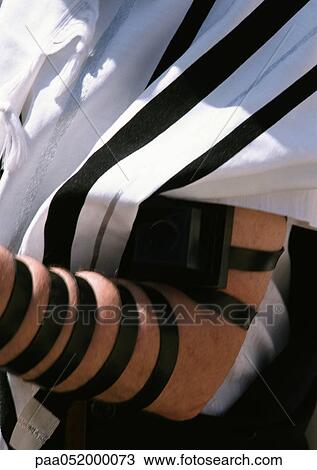 Stock Image - Person wearing tefillin, focus on arm. Fotosearch