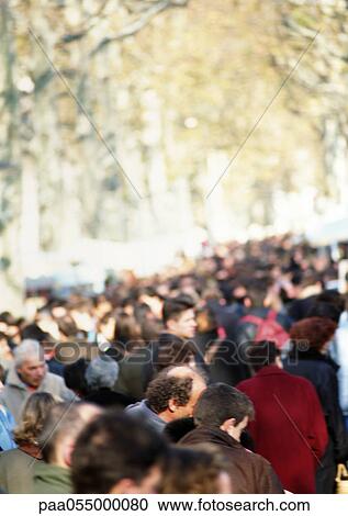 Stock Image - Crowd, trees in background, blurred. Fotosearch