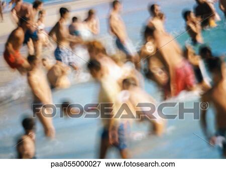 Stock Photo - People standing in water at beach, blurred. Fotosearch