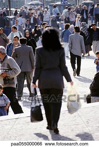 Stock Photograph - Woman walking in crowded street, rear view, blurred. Fotosearch