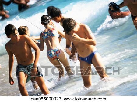 Young people standing knee-deep in water at beach View Large Photo Image Stock Image - Young people standing knee-deep in water at beach. Fotosearch