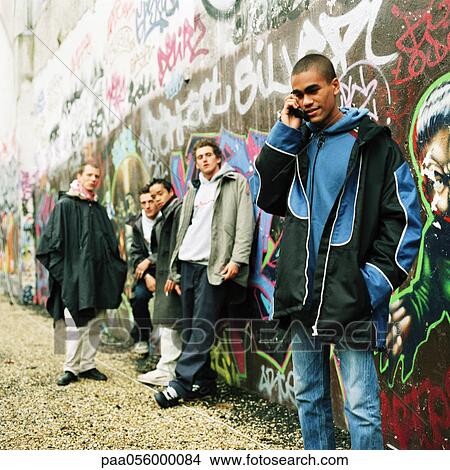 Picture - Five young men in front of wall covered in graffiti. Fotosearch