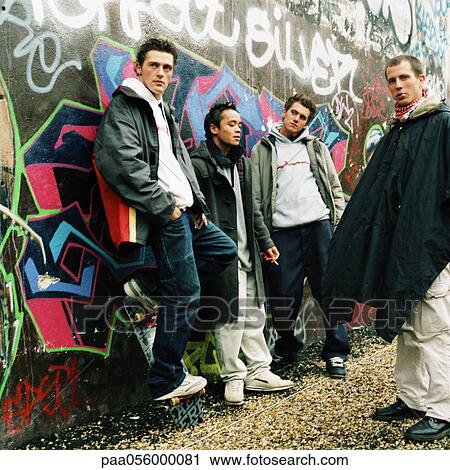 Four young men in city street, three leaning against graffiti wall View Large Photo Image Stock Image - Four young men in city street, three leaning against graffiti wall. Fotosearch