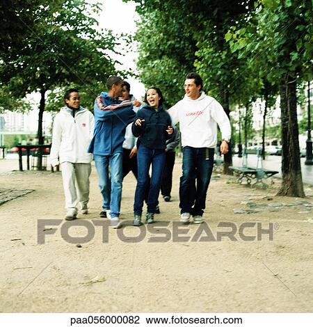 Stock Image - Group of teenagers walking in park side by side. Fotosearch