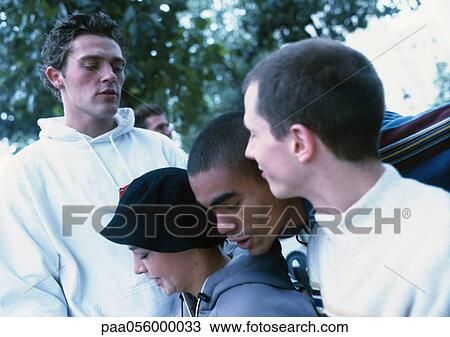 Stock Image - Group of young people outside, tree in background. Fotosearch