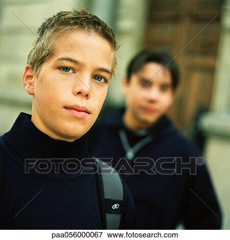 Stock Photo - Teenage boy looking into camera, second teenager in background. Fotosearch