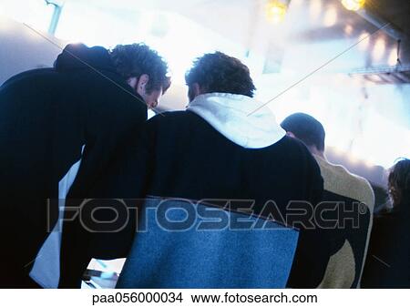 Picture - Three men standing side by side, rear view. Fotosearch