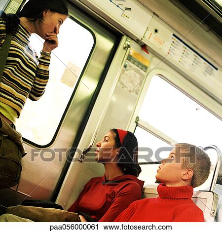 Stock Image - Three teenagers in subway train. Fotosearch