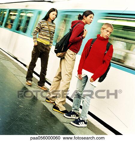 Stock Image - Three teenagers standing on platform, blurred motion. Fotosearch