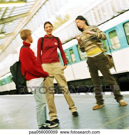 Stock Photo - Three teenagers standing on subway platform, blurred. Fotosearch