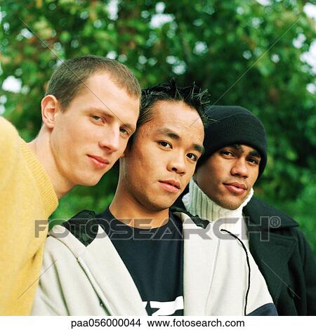 Picture - Three young men looking into camera, low angle view. Fotosearch