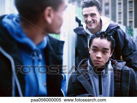 Three young men outside, building in background View Large Photo Image Stock Photography - Three young men outside, building in background. Fotosearch