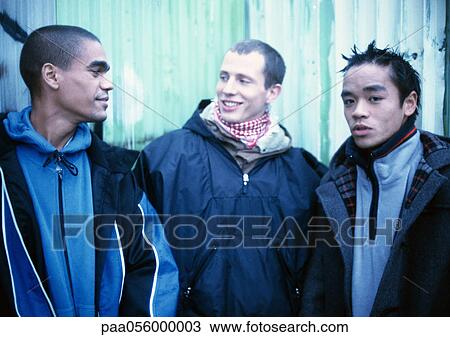 Stock Image - Three young men standing side by side. Fotosearch