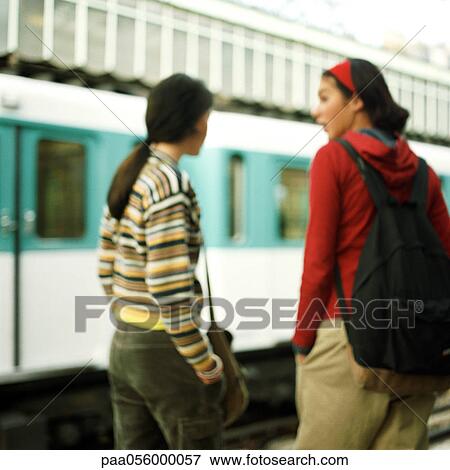 Stock Photo - Two teenagers waiting on platform, rear view, blurred. Fotosearch