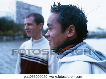 Two young men, outside, river in background View Large Photo Image Stock Photo - Two young men, outside, river in background. Fotosearch