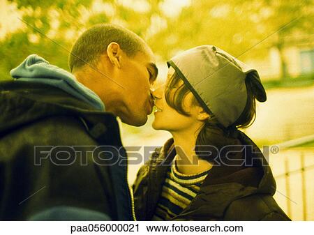 Stock Image - Young couple kissing, side view. Fotosearch