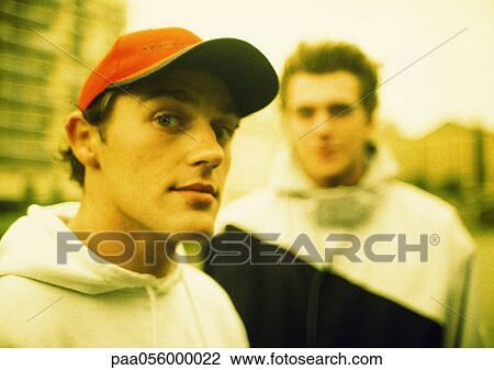 Young man looking into camera, second young man in background View Large Photo Image Stock Image - Young man looking into camera, second young man in background. Fotosearch
