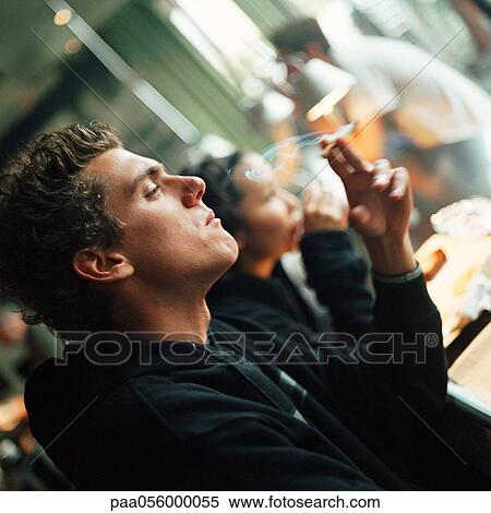 Young man smoking a cigarette, side view View Large Photo Image Stock Photography - Young man smoking a cigarette, side view. Fotosearch