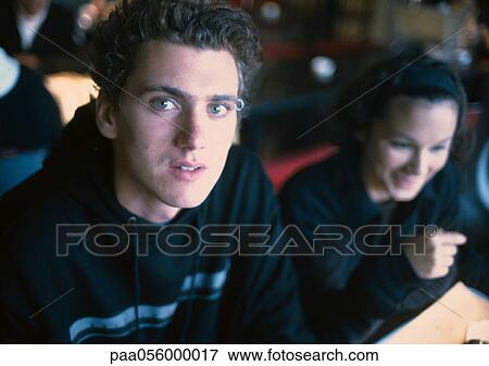 Stock Photo - Young people sitting, boy looking into camera. Fotosearch