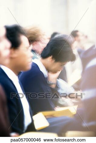 Stock Photograph - People sitting side by side during mass, side view, close-up, blurred. Fotosearch
