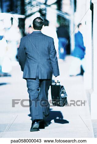 Businessman walking in street, rear view View Large Photo Image Stock Image - Businessman walking in street, rear view. Fotosearch
