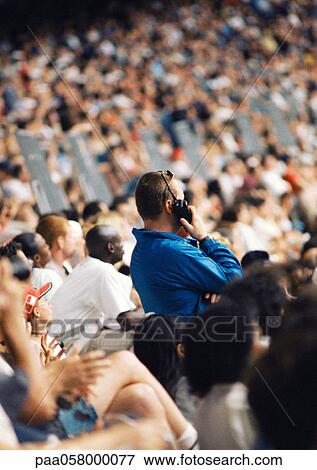 Man standing in crowd, holding walkie-talkie View Large Photo Image Stock Photo - Man standing in crowd, holding walkie-talkie. Fotosearch