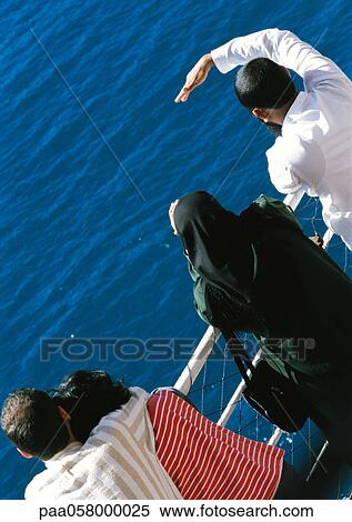 Stock Photography - People leaning on rail, looking out to sea, high angle view. Fotosearch