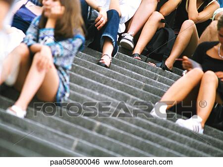 Stock Photograph - People sitting on stairs, low angle view. Fotosearch