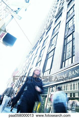 Stock Image - People walking in street, low angle view, tilt, blurred. Fotosearch