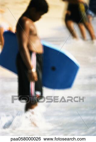 Person holding bodyboard, feet in water, blurred View Large Photo Image Stock Photograph - Person holding bodyboard, feet in water, blurred. Fotosearch