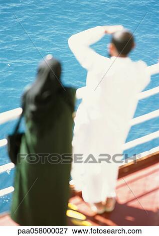 Stock Photo - Two people leaning on rail, looking out to sea, blurred. Fotosearch